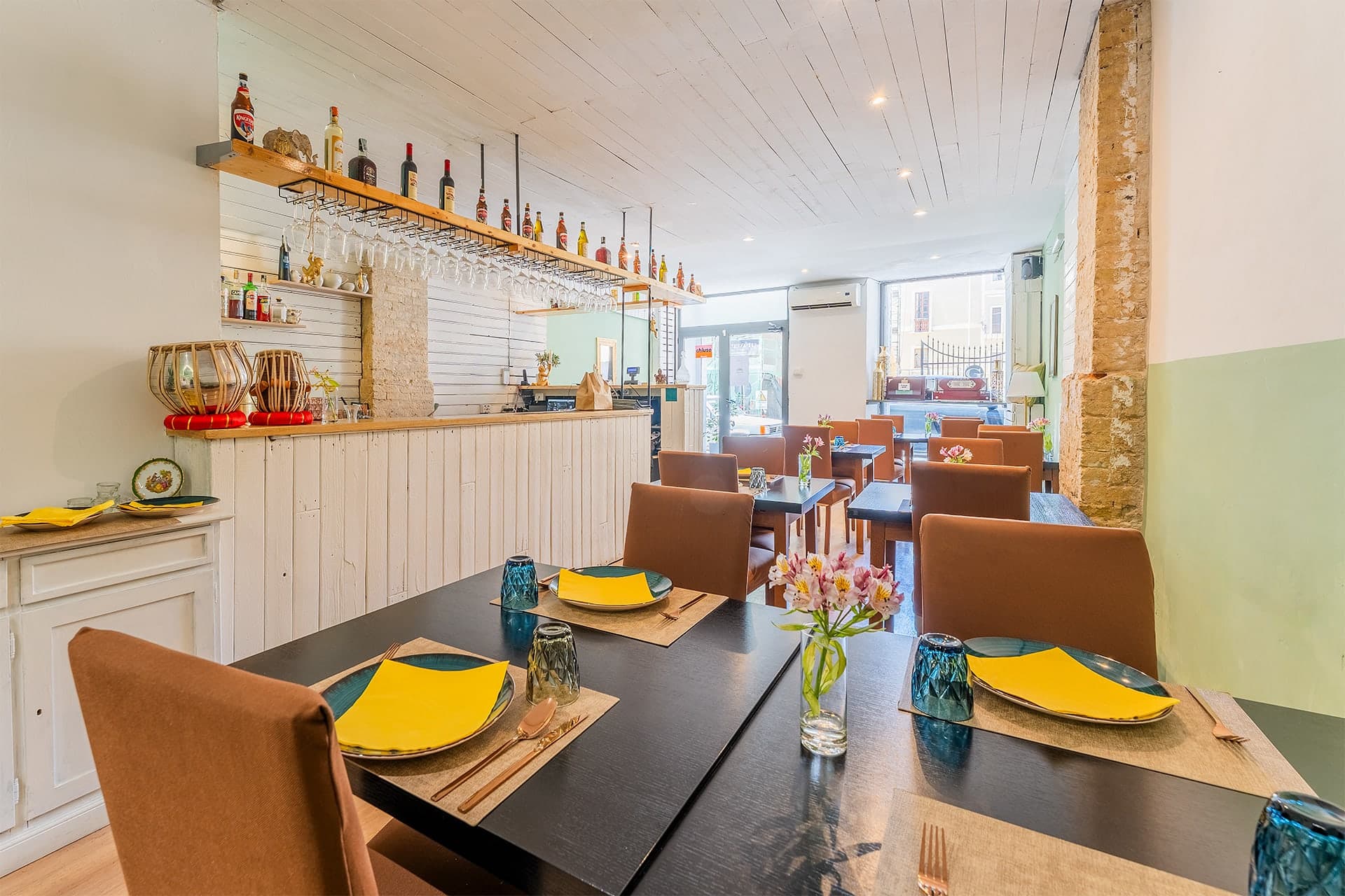 Rasvati restaurant dining room with yellow napkins and sage green walls